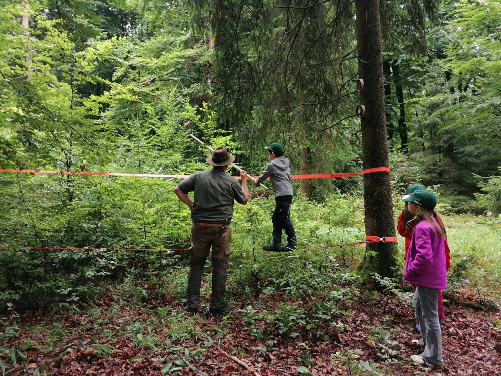 Beim Balancieren auf der Slackline gibt ein Erwachsener Hilfestellung.