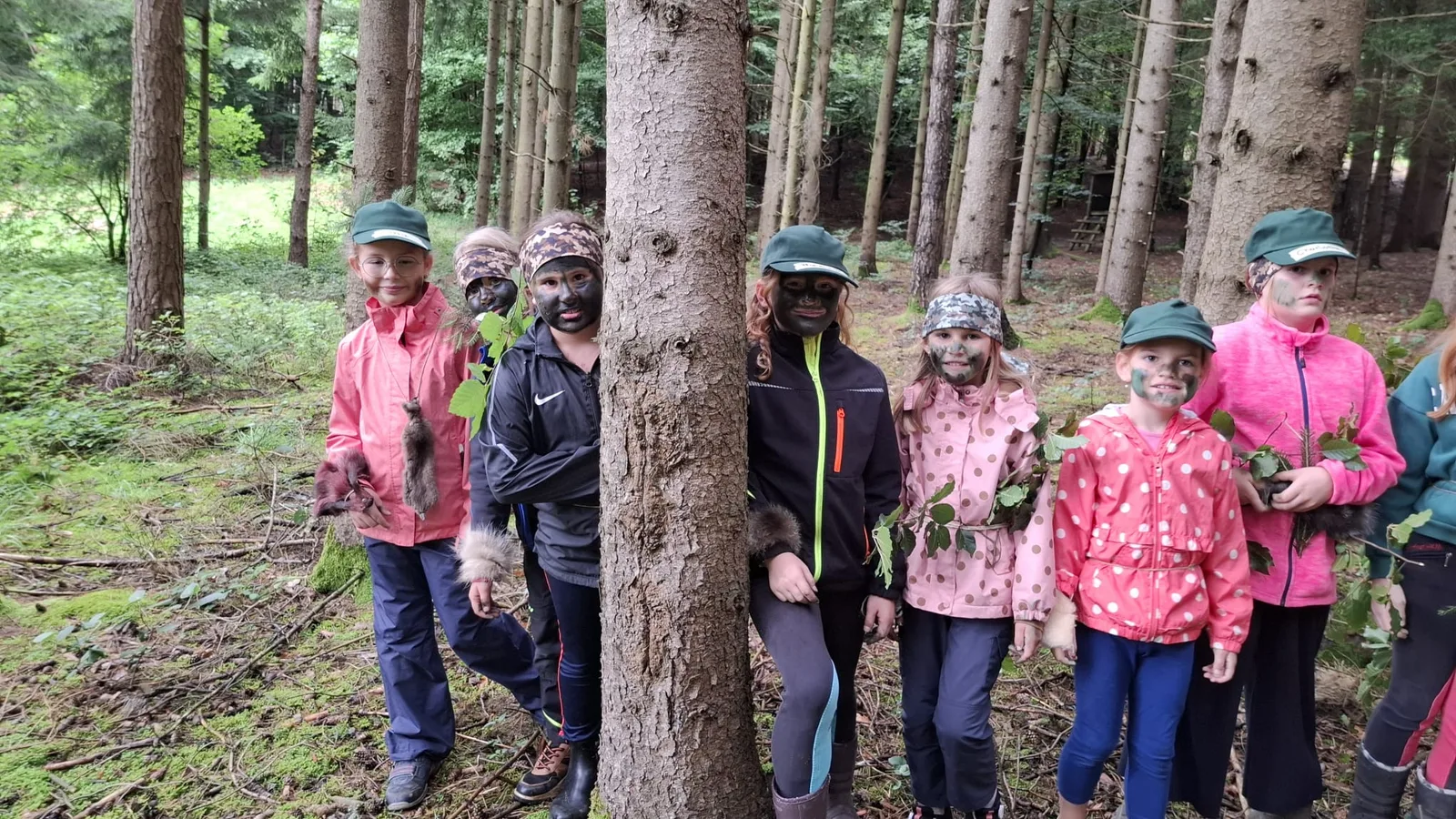 Kinder mit Naturmaterialien und bemalten Gesichtern.