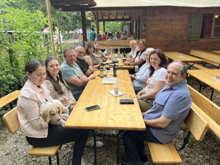 Festgäste vor der Vereinshütte, mit einem Hund am Tisch.